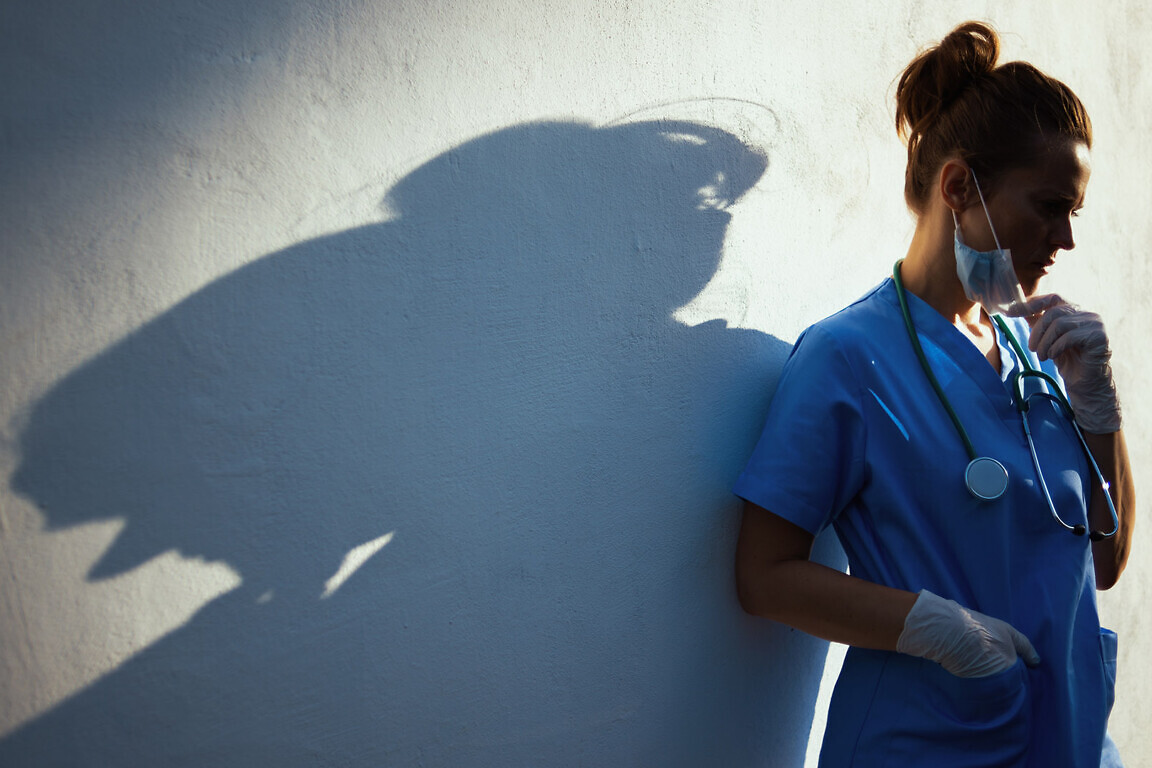 stressed medical doctor woman outdoors in city near wall