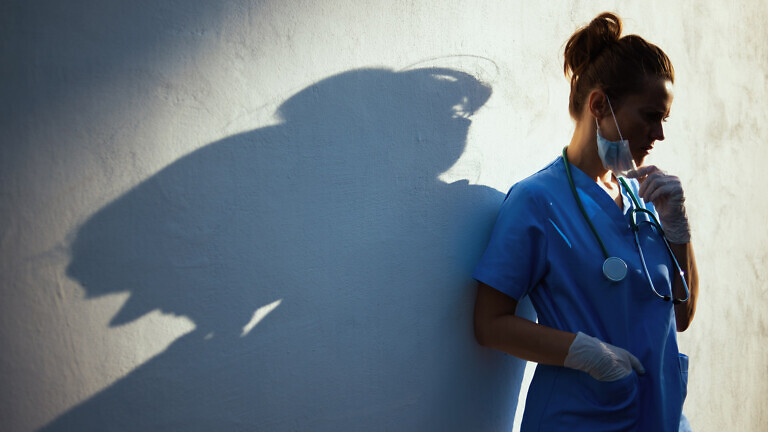stressed medical doctor woman outdoors in city near wall