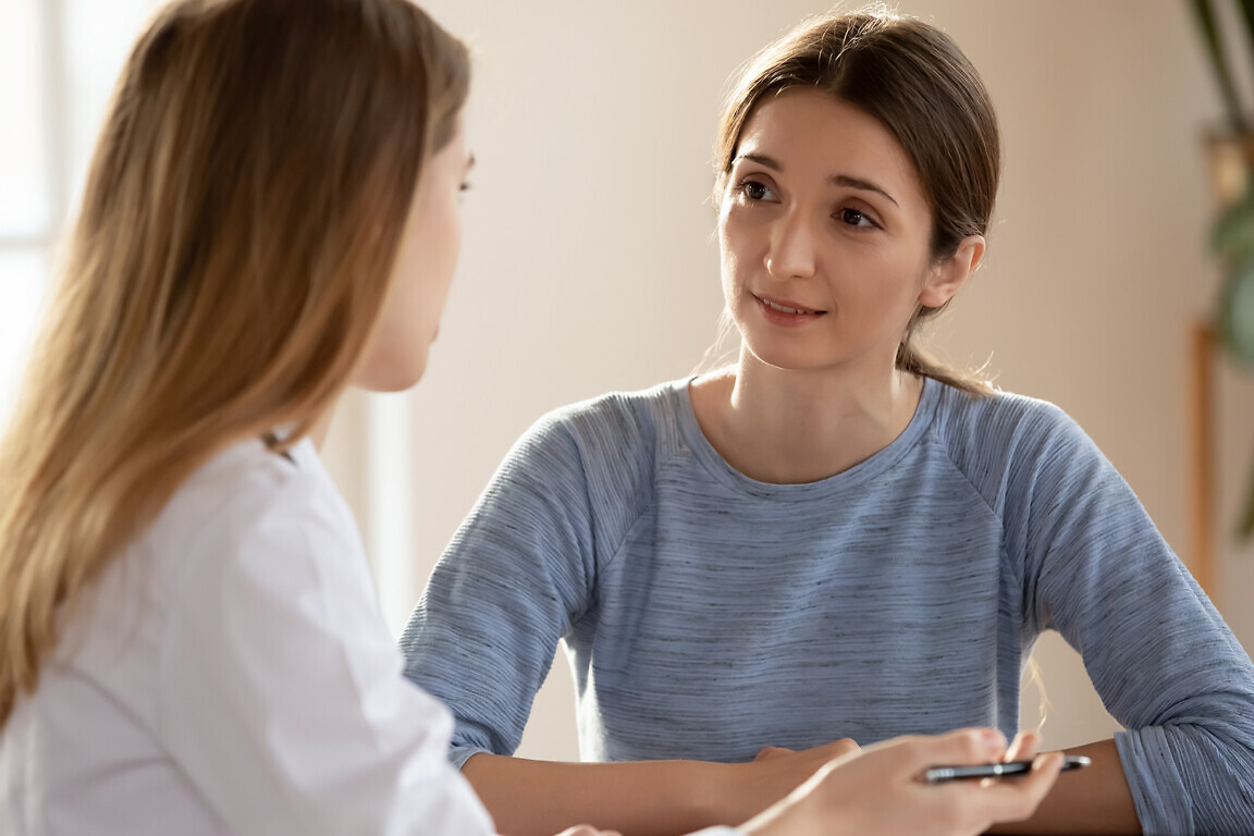 Millennial female visitor of clinic discussing problem with trusted physician