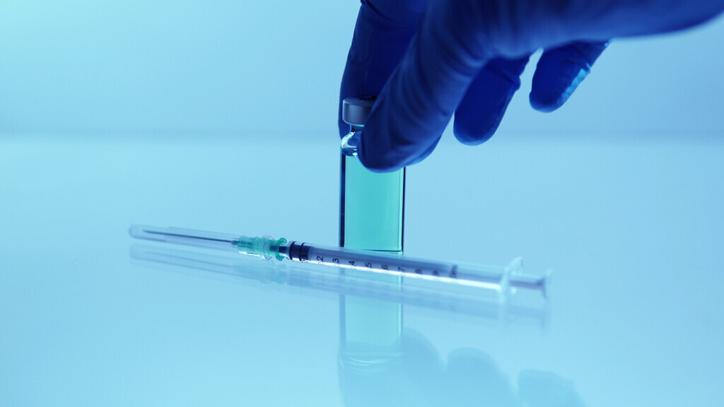 Medical vaccine scientist holding the glass vial with vaccine.