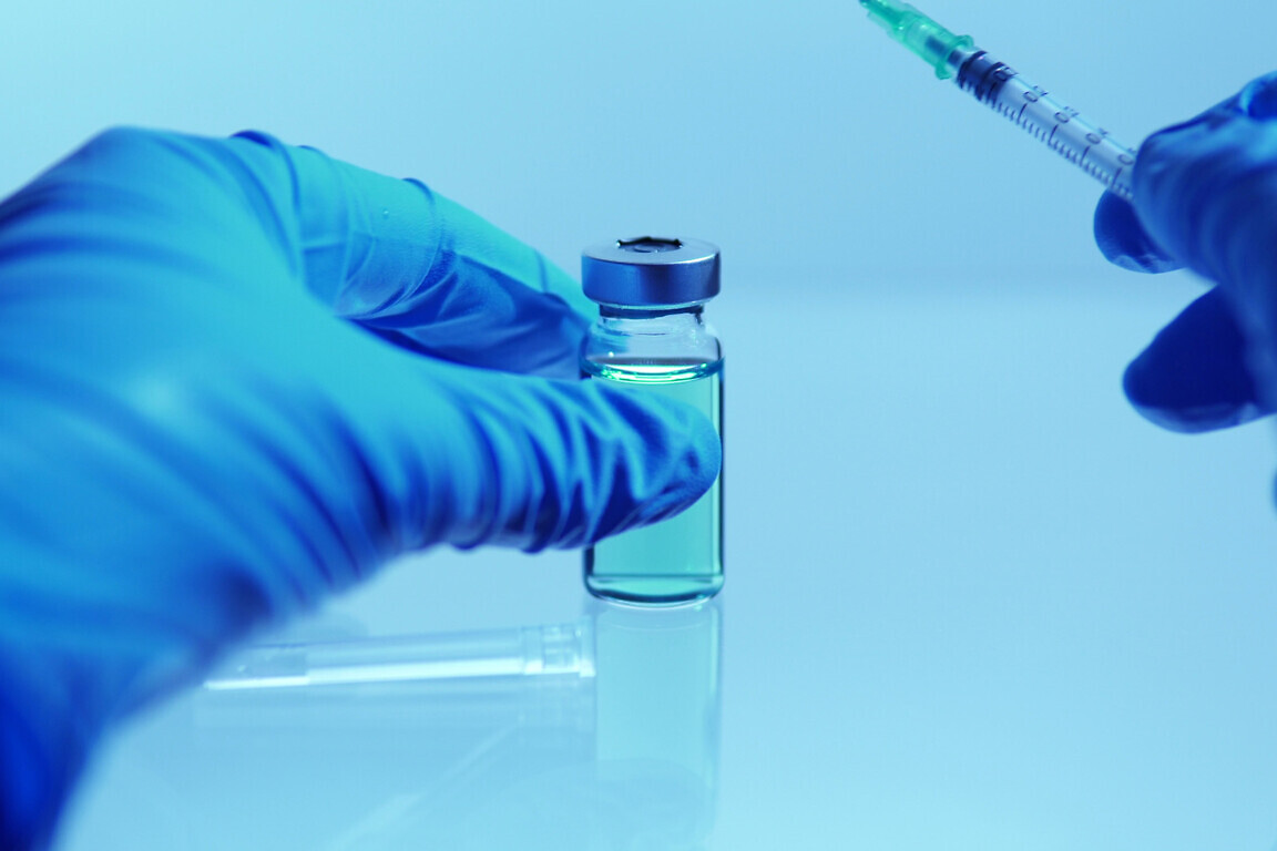 Vaccine and infectious disease developing concept. Doctor holding sterile vial with blue medication against coronavirus, COVID-19. Clinical trials development and testing on human depiction.