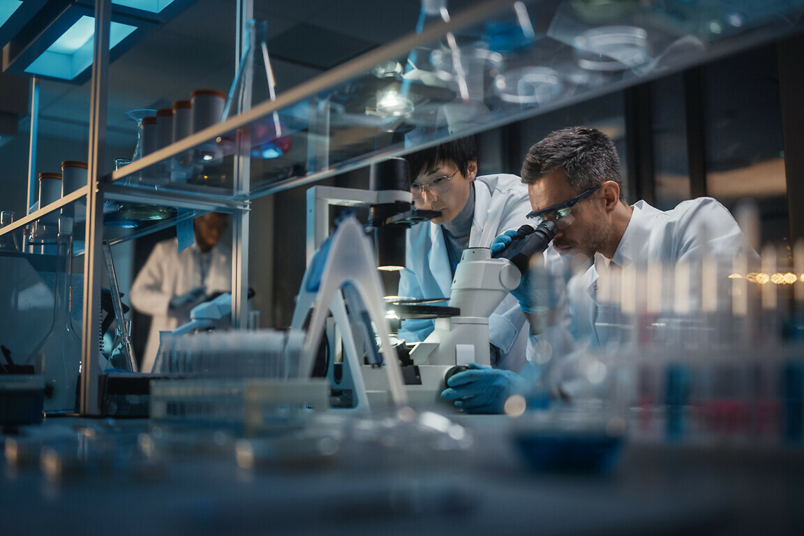 Modern Medical Research Laboratory: Team of East Asian and Caucasian Scientists Work on Laptop, do Data Analysis, Use Microscope. Advanced Lab for Medicine, Biotechnology Development.