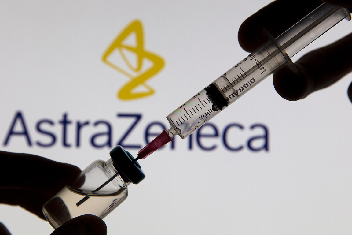 Covid vaccine syringe in front of Astrazeneca logo.