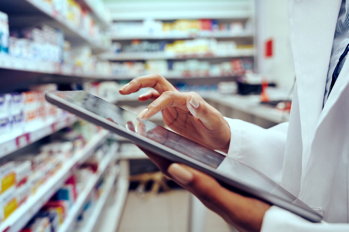 Closeup of hands of young female pharmacist checking inventory using digital tablet