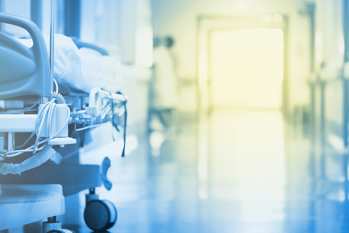 Mysterious, enchanting light in a hospital hallway with a bed in the foreground.