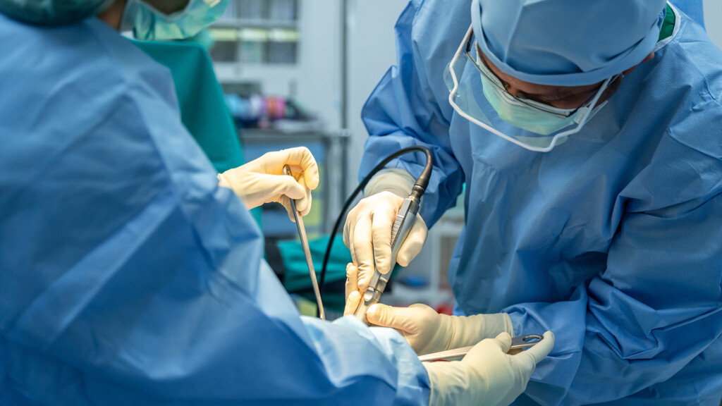Medical team of surgeons and assistant in hospital doing orthopedic surgery.