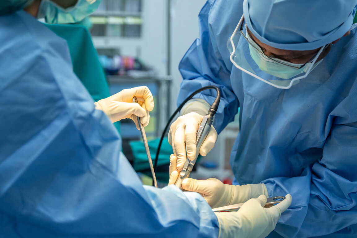 Medical team of surgeons and assistant in hospital doing orthopedic surgery.
