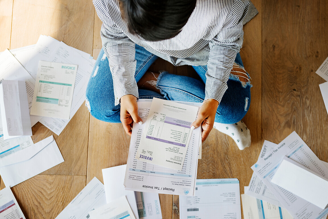 Sorting out a pile of bills on the floor