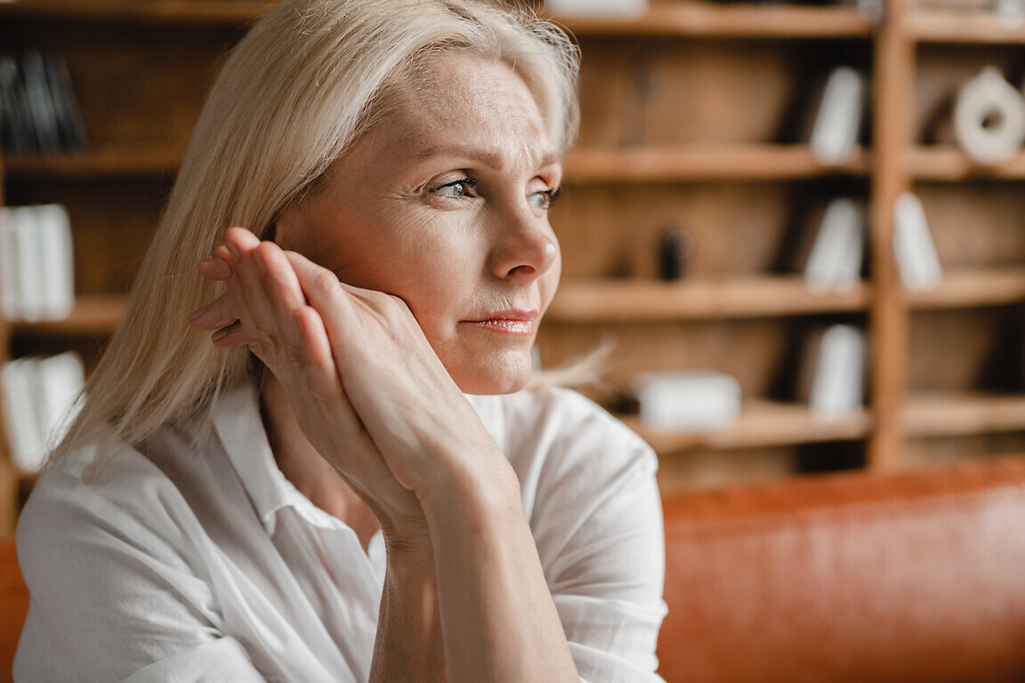 Stressed sad tired exhausted caucasian middle-aged mature businesswoman freelancer relaxing on the couch sofa, thinking about family marriage work problems at work office