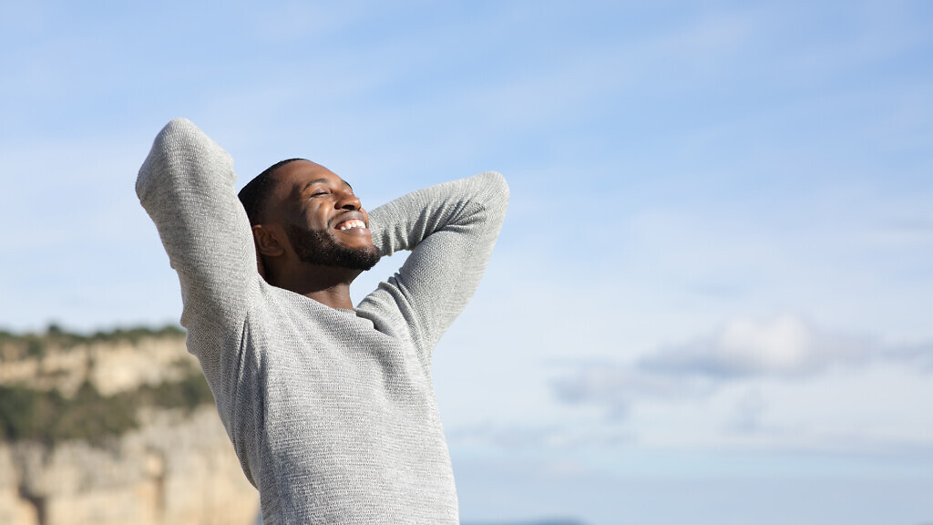 Relaxed man with black skin breathing in the mountain