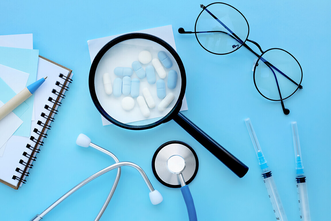 medical mockup, pharmaceutical pills, tablets, capsules under a magnifying glass on a pastel blue background. Minimal modern pharmacy or healthcare concept.Flat lay.