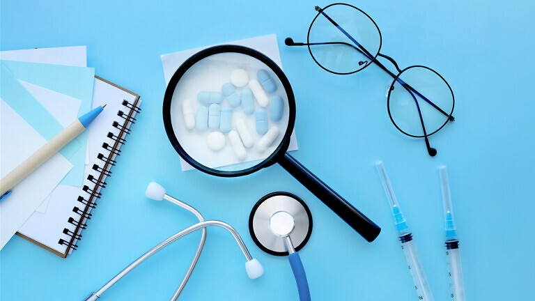 medical mockup, pharmaceutical pills, tablets, capsules under a magnifying glass on a pastel blue background. Minimal modern pharmacy or healthcare concept.Flat lay.