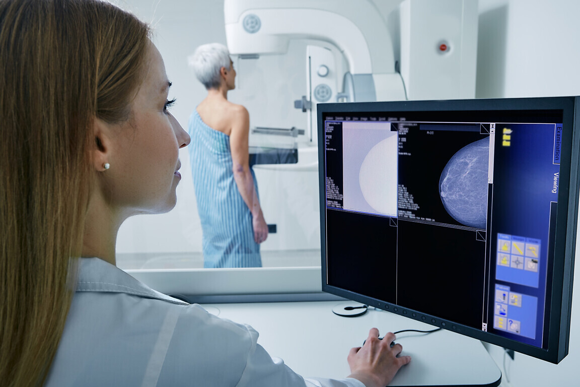 Medical technician taking mammogram exam to female patient.