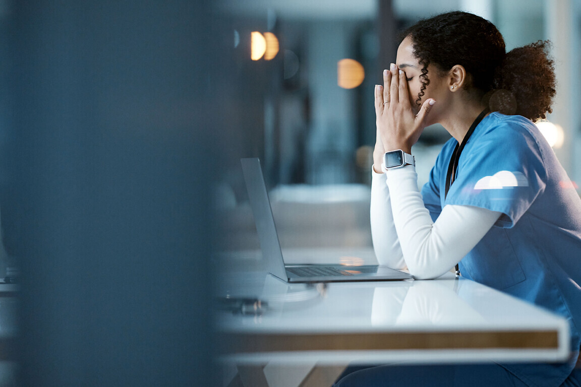 Nurse, burnout stress and black woman in hospital feeling pain, tired or sick on night shift. Healthcare, wellness and female medical physician with depression or anxiety while working late on laptop