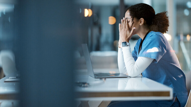 Nurse, burnout stress and black woman in hospital feeling pain, tired or sick on night shift. Healthcare, wellness and female medical physician with depression or anxiety while working late on laptop
