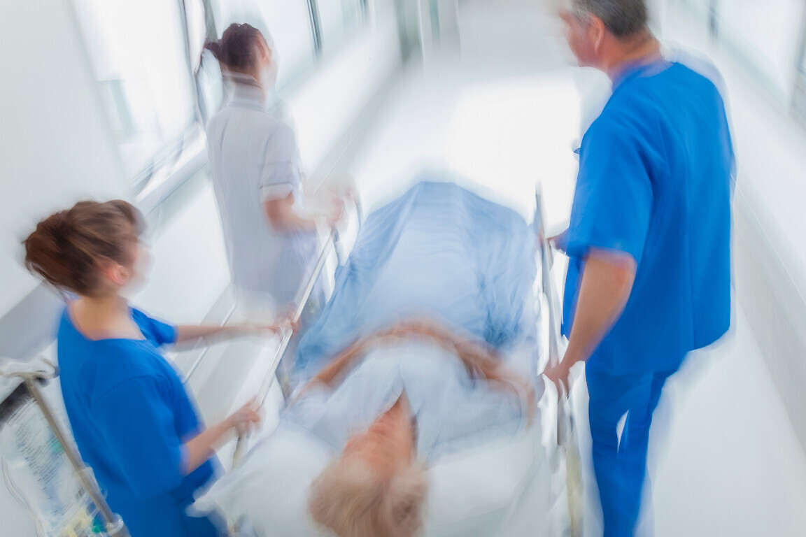 A motion blurred photograph of a senior female patient on stretcher.