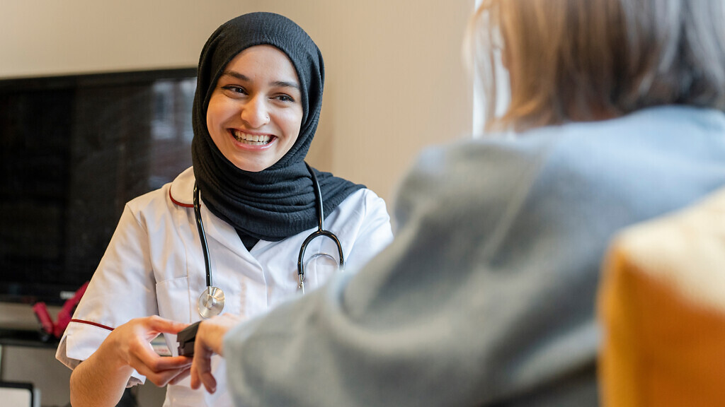Smiling doctor using pulse oximeter on patient