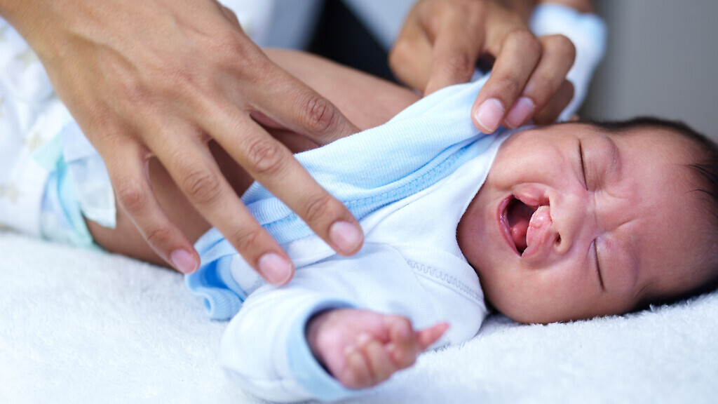 Newborn, cleft palate and mother care for a baby crying in a home bed feeling tired in a bedroom or medical centre. Health, healthcare and young child or kid sad and parent give love and comfort.