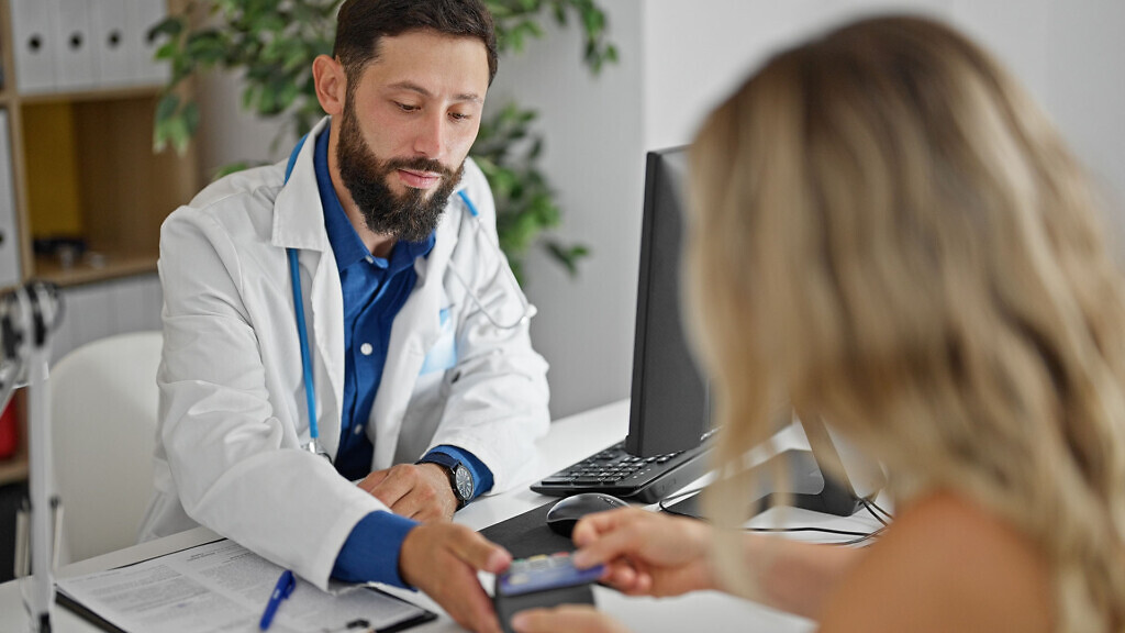 Young doctor charging medical consultation to patient at the clinic