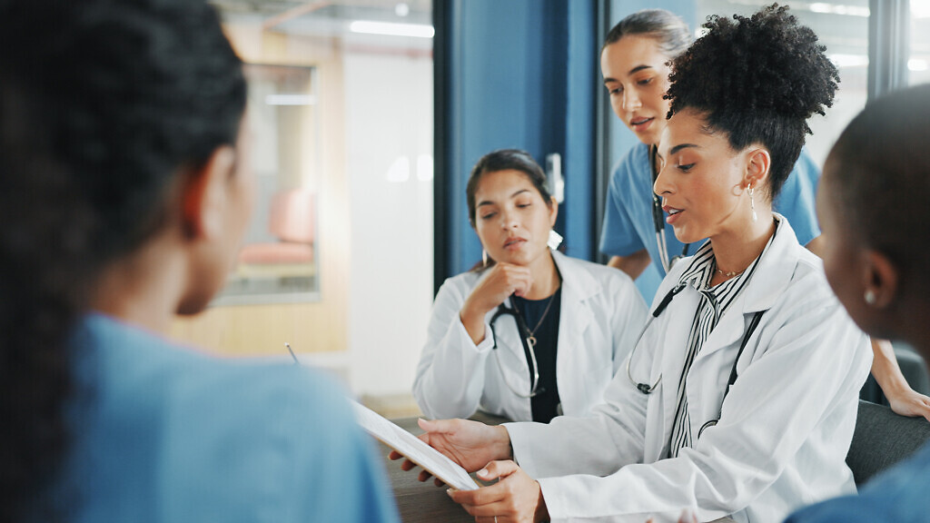 Doctors, nurse and women on clipboard in meeting, collaboration or teamwork for hospital planning, medical or life insurance. Talking, leadership and healthcare workers on paper in diversity research