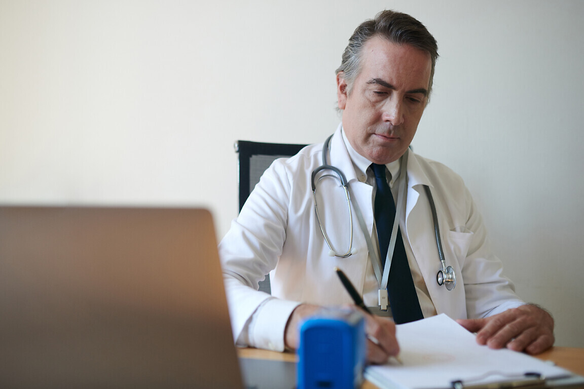 Head of hospital signing contracts and documents at his desk