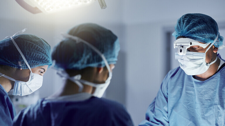 Surgery, team and mask on face with glasses for medical, healthcare and working in operation room. Surgeon, teamwork and people in hospital or clinic for healing, treatment or kidney transplant.