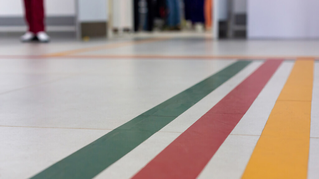 Colorful guide lines on the floor of the hospital corridor for navigation with a blurred hospital background