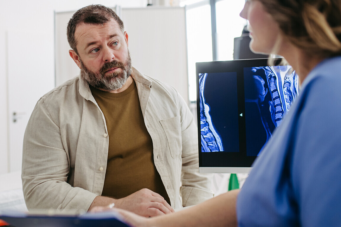 Doctor consulting with overweight patient, discussing test result and x-ray scans in doctor office. Concept of health risks of overwight and obesity.