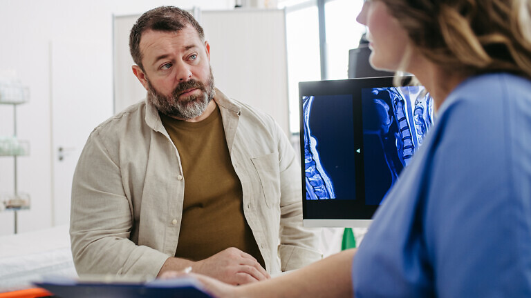 Doctor consulting with overweight patient, discussing test result and x-ray scans in doctor office. Concept of health risks of overwight and obesity.