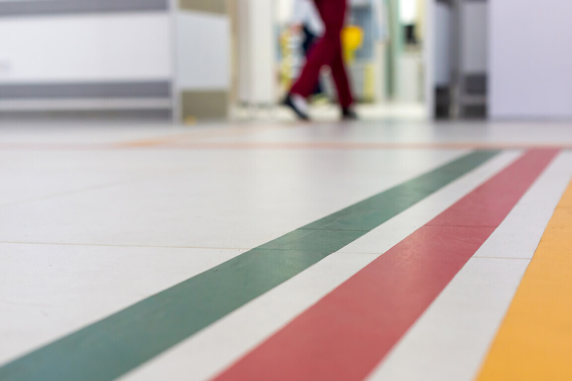 Colorful guide lines on the floor of the hospital corridor for navigation with a blurred hospital background