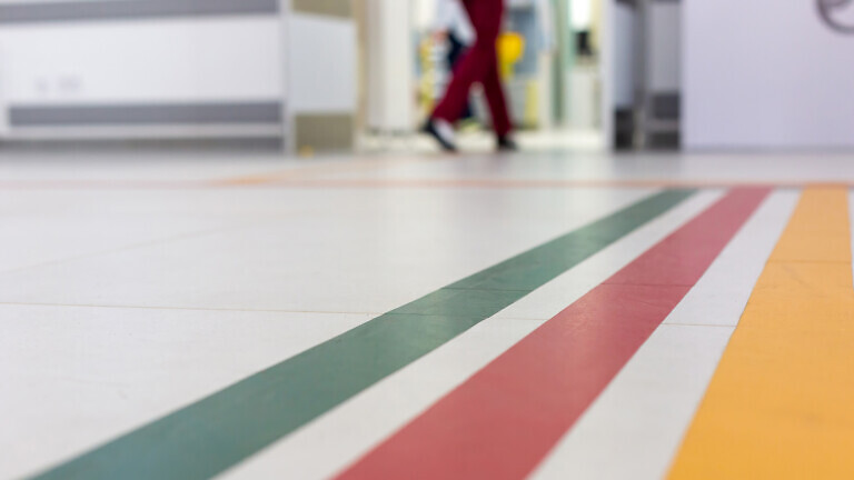 Colorful guide lines on the floor of the hospital corridor for navigation with a blurred hospital background