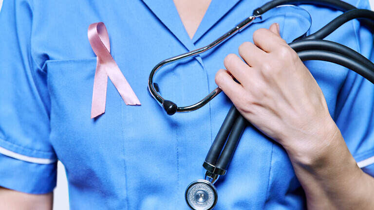 Close-up female nurse with with stethoscope, pink ribbon