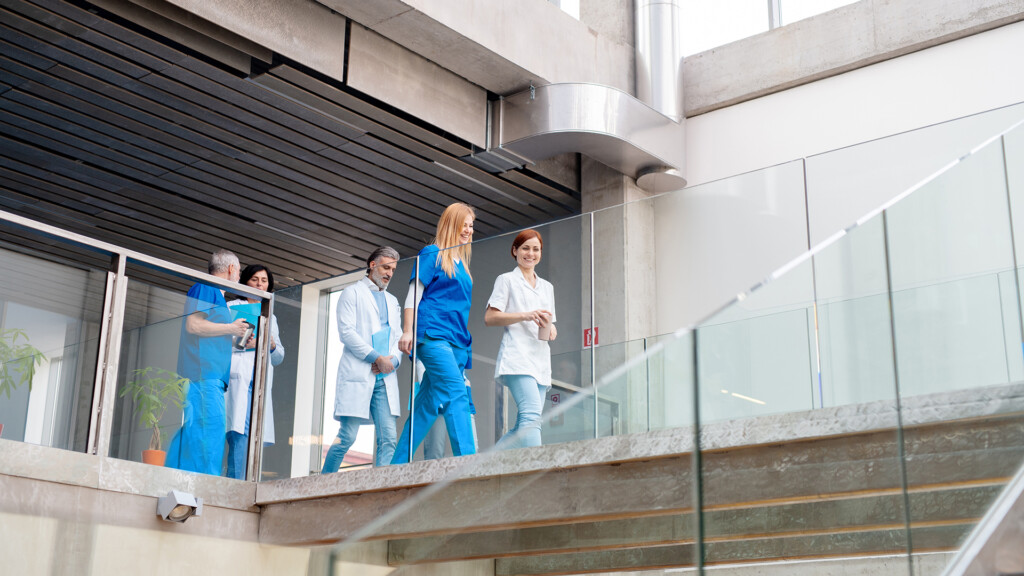 Team of doctors walking across hospital corridor. Colleagues, doctors team discussing medical case.
