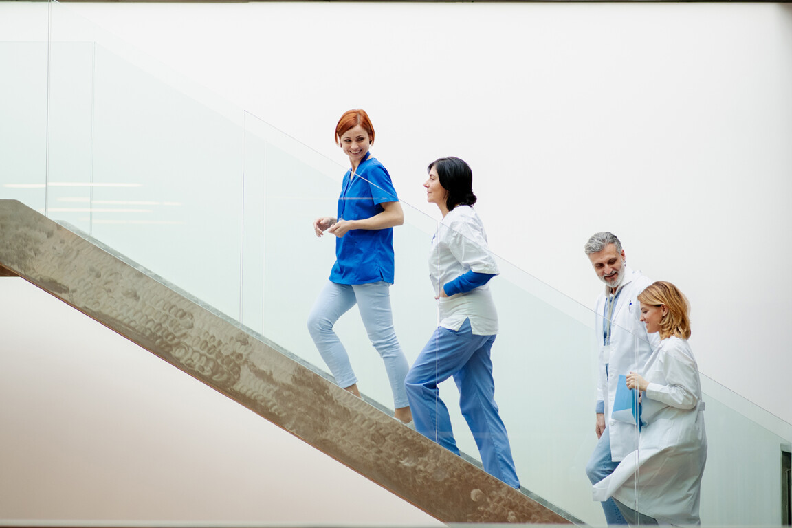 Portrait of team of doctors standing on modern stairs. Healthcare team with doctors, nurses, professionals in medical uniforms in hospital, modern clinic.
