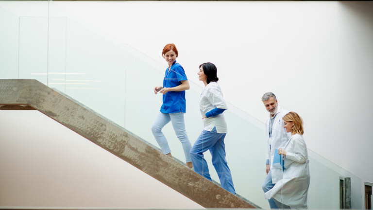 Portrait of team of doctors standing on modern stairs. Healthcare team with doctors, nurses, professionals in medical uniforms in hospital, modern clinic.
