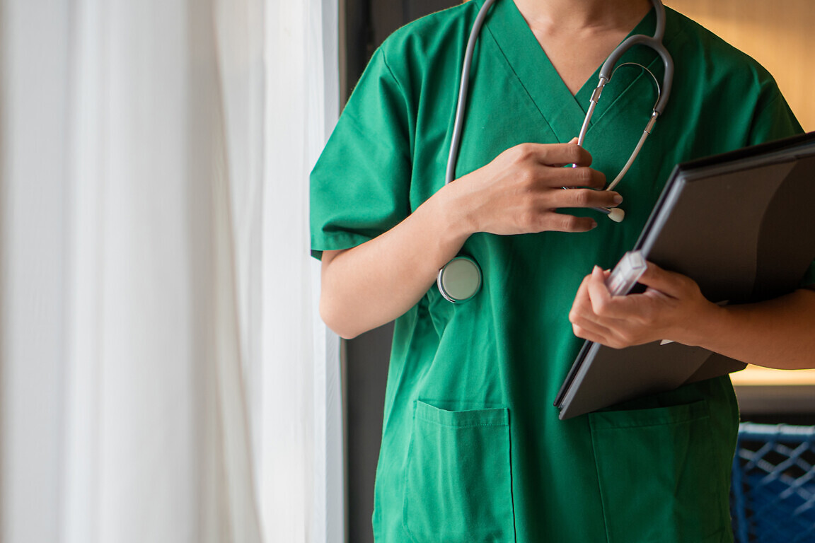 Female doctor with lab coat in her office holding a clipboard