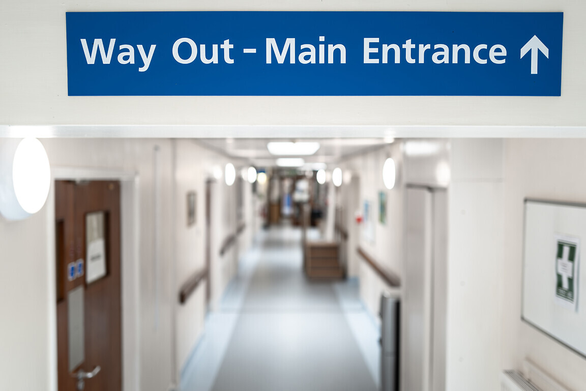 Shallow focus of a Way Out and Main Entrance sign seen within th