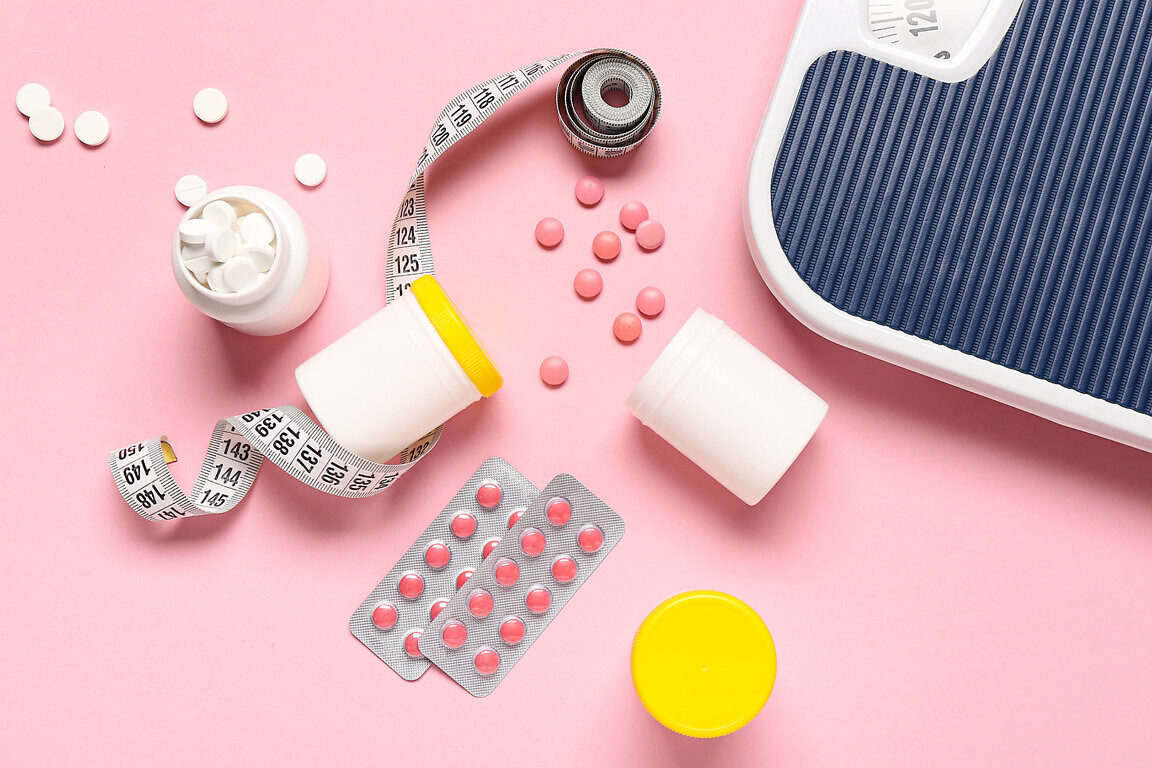 Bottles with weight loss pills, scales and measuring tape