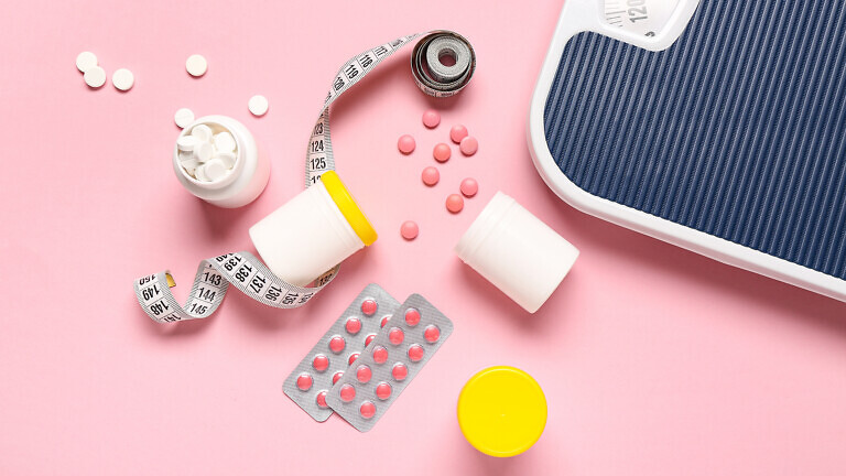 Bottles with weight loss pills, scales and measuring tape