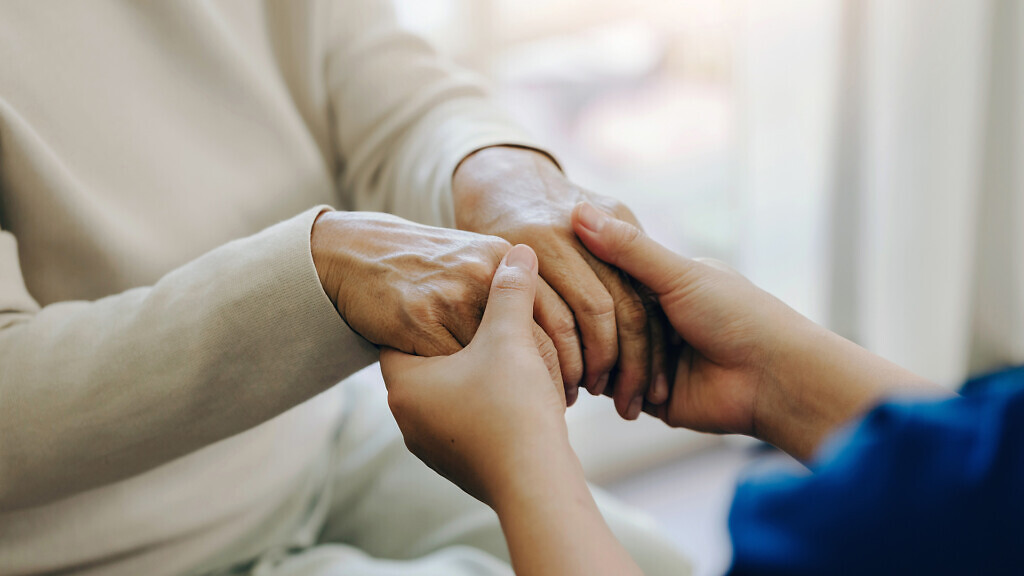 Female nurse holding her senior patient's hand. Giving Support.