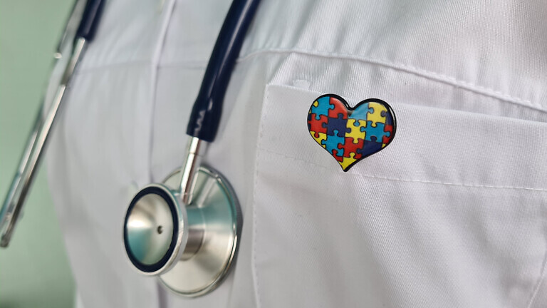 A Doctor Wearing a Stethoscope and a Puzzle Piece Heart Pin