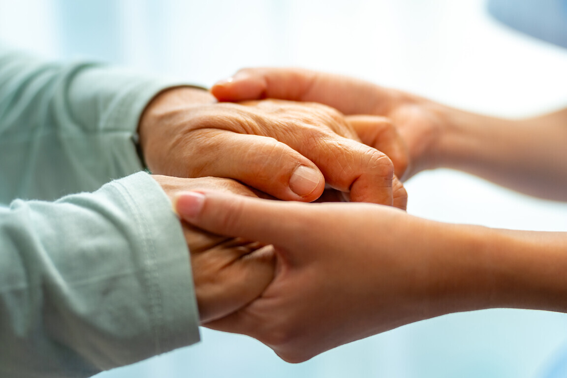 Woman doctor consoling senior patient with holding her hand.