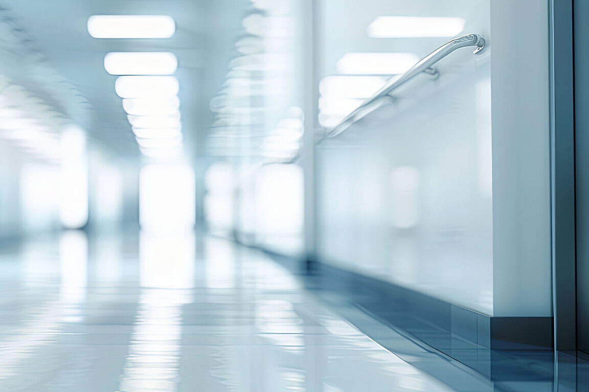 Abstract blurred background of a modern office building hallway with bright windows and white tiled floors.