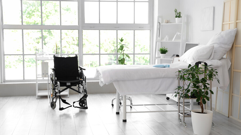 Interior of hospital ward with bed and wheelchair