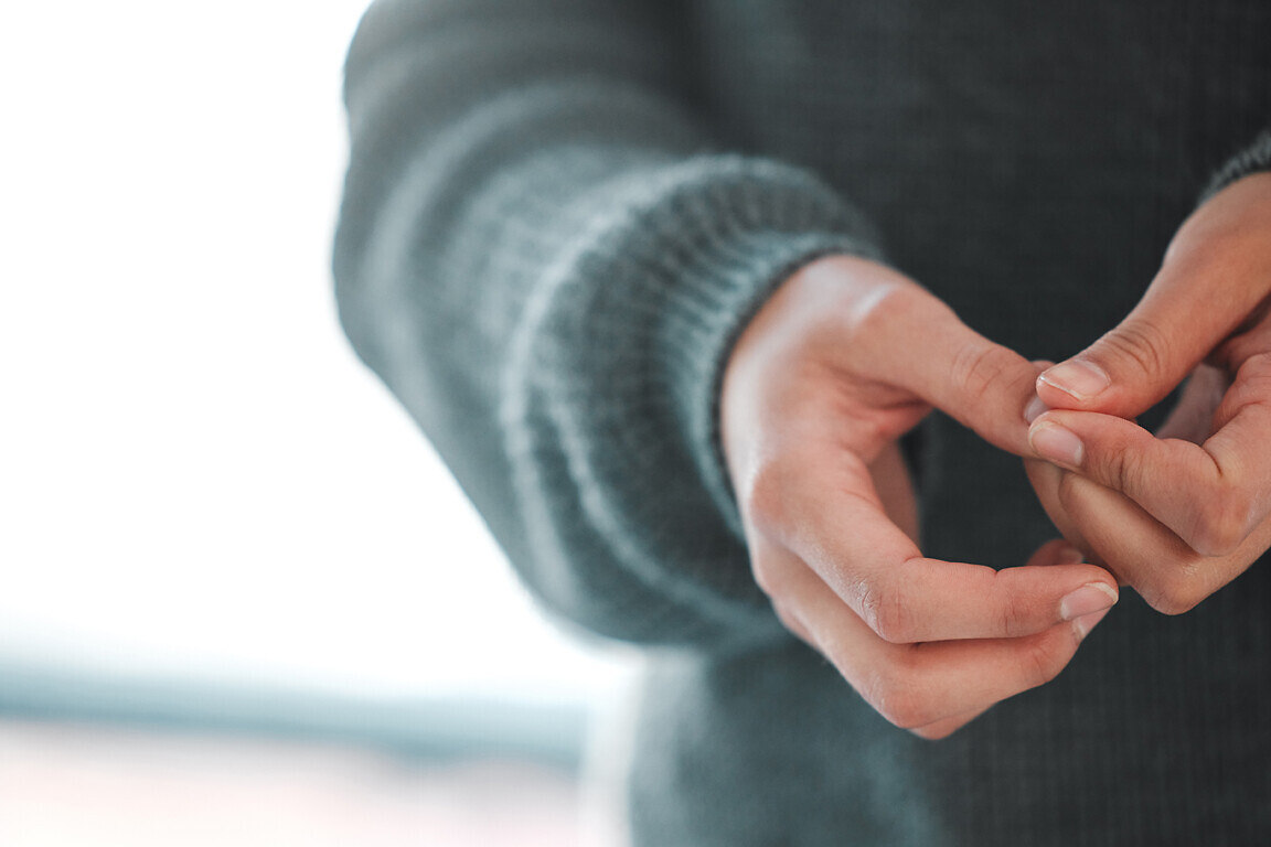 Hands, anxiety and person in counseling for therapy, trauma or mental health in psychologist office. Woman, fidgeting or PTSD in session for depression, paranoia or memory at consultation for healing