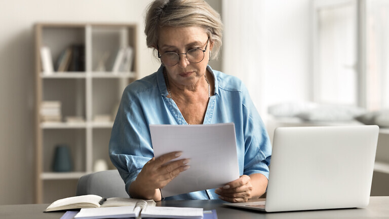 Older woman with serious expression reading document