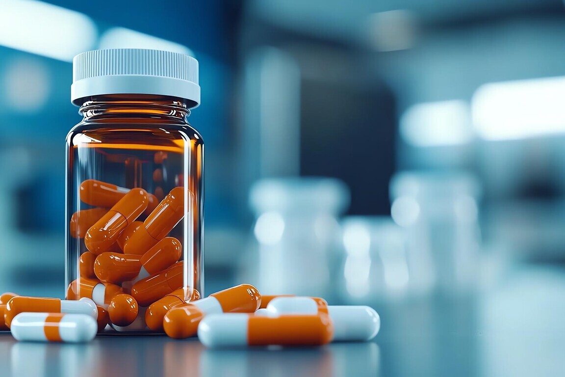 Orange and white capsules in a clear bottle on a blurred background.